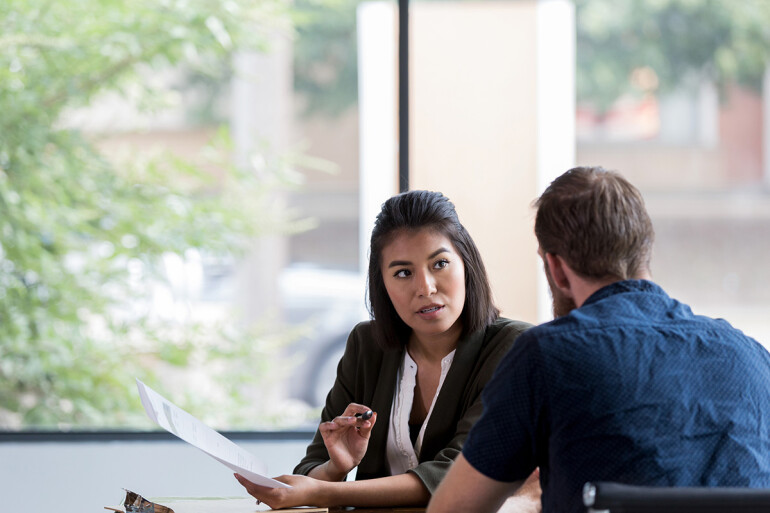 Two people in a meeting review a document