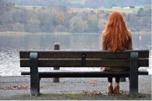 Girl on bench looks out at a lake